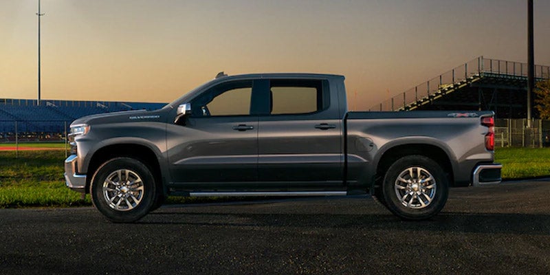 Side profile of blue Chevrolet Silverado 1500 on a bridge at sunset