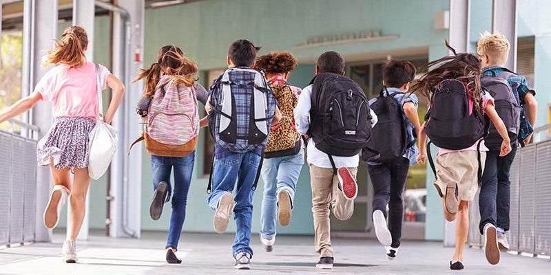 Group Of A School Kids With Backpack Running Towars A Wall