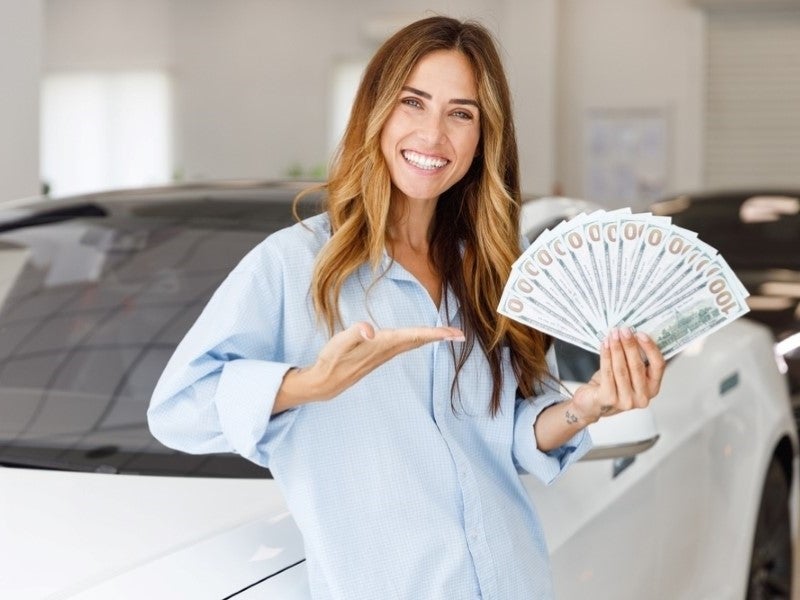 Woman Customer Holding Cash In Her Hand Stood Beside A Vehicle