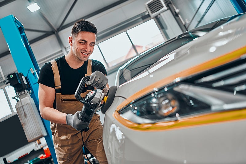 Male Service Person Doing Servicing Of Exterior Of A Vehicle