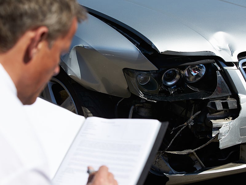 Male Advisor Inspecting A Damaged Vehicle